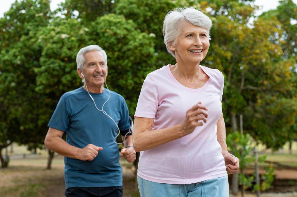 Senior couple jogs together, revitalized by exosome therapy.