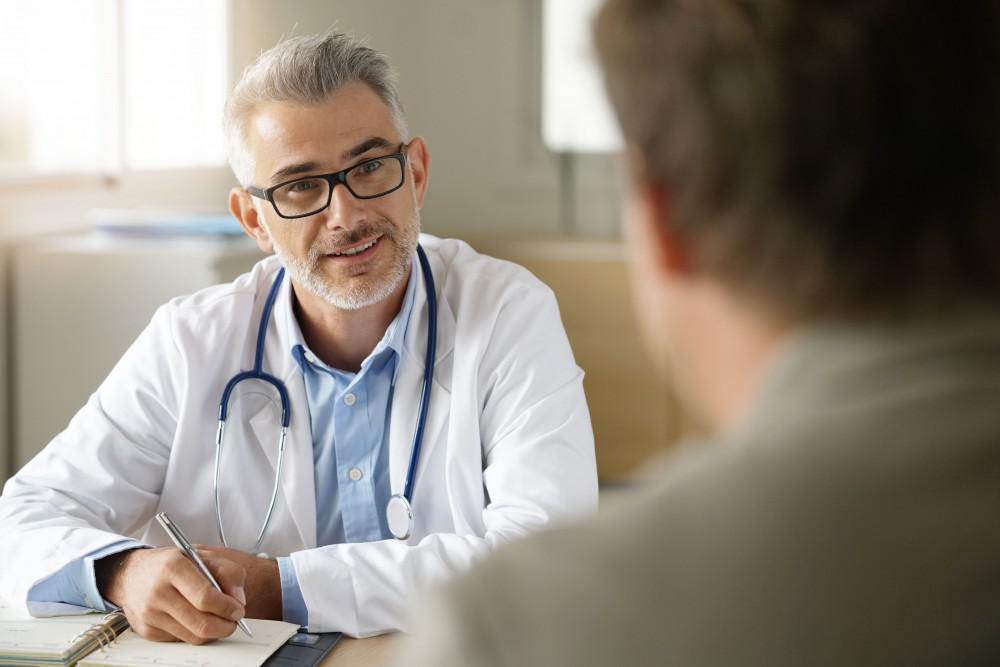 Doctor smilingly discusses medication management with patient.