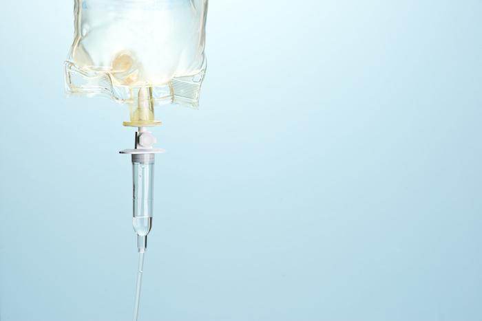 Close-up of an infusion therapy IV bag against a blue backdrop.