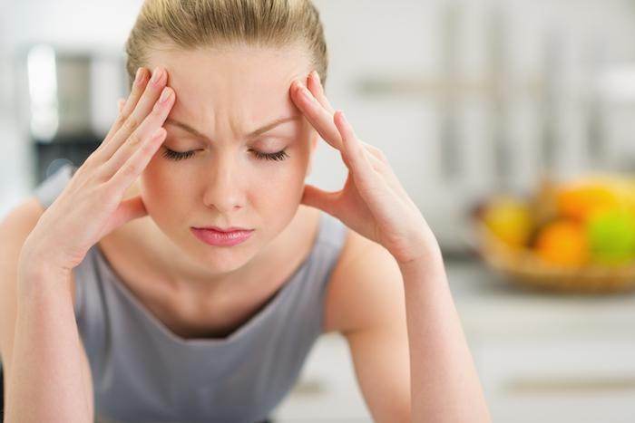 Woman with pained expression, considering triggers for migraines.