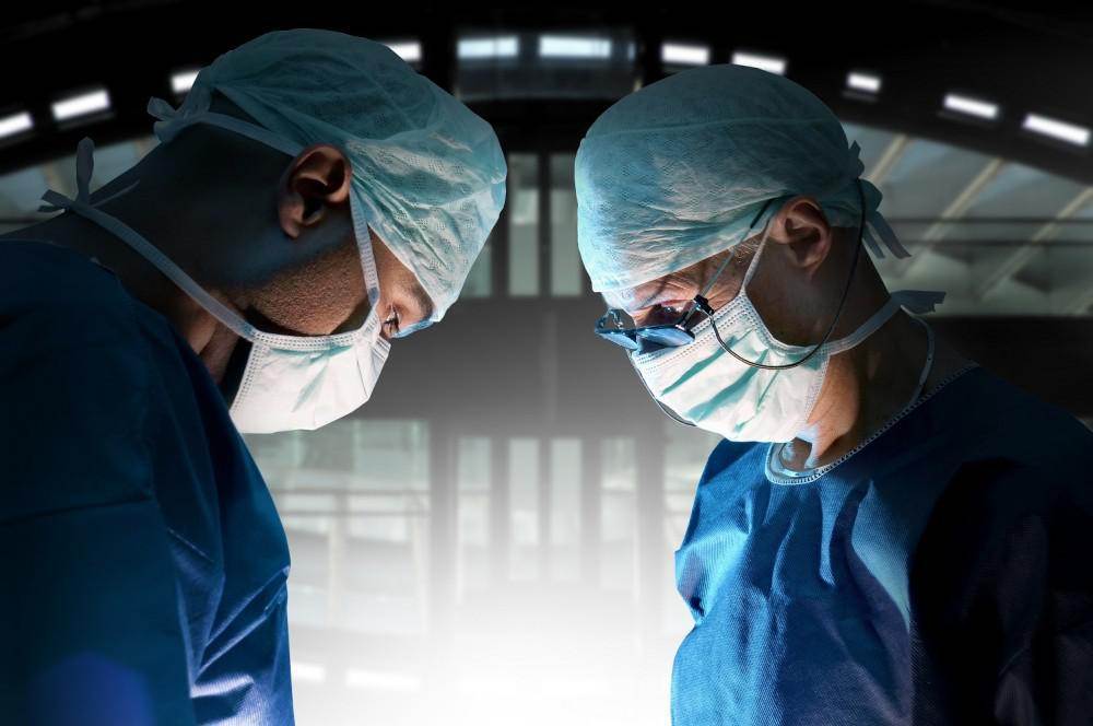 Surgeons in scrubs perform kyphoplasty in an operating room.