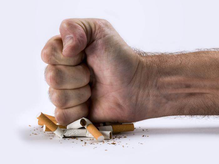 Hand crushes cigarettes, symbolizing fight against nociceptive pain.