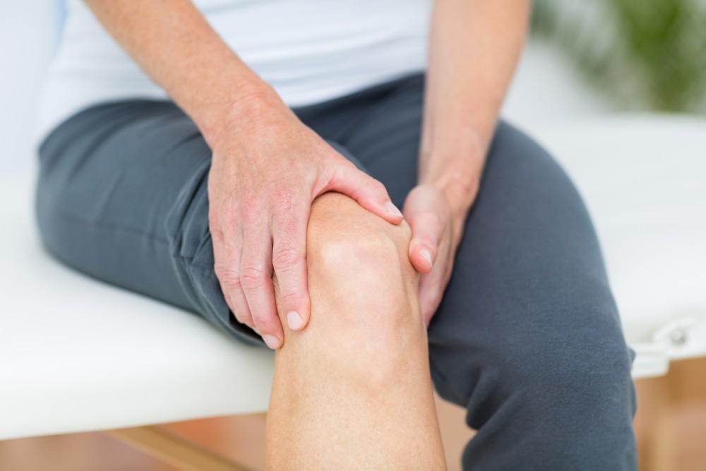 Man grasping knee, possibly due to nociceptive pain.