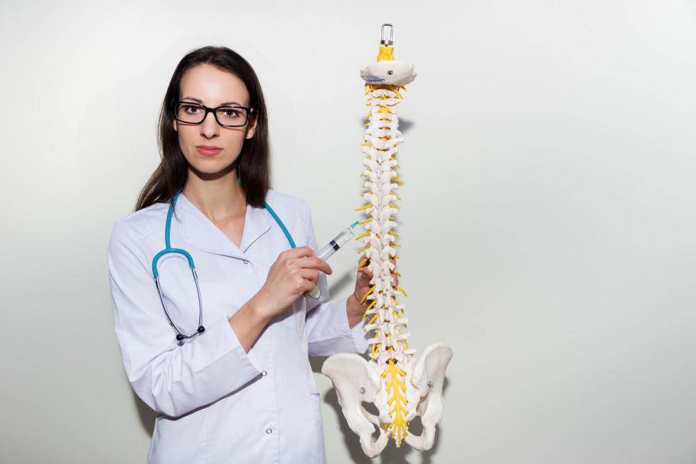 Doctor with spine model, indicative of a spinal stenosis